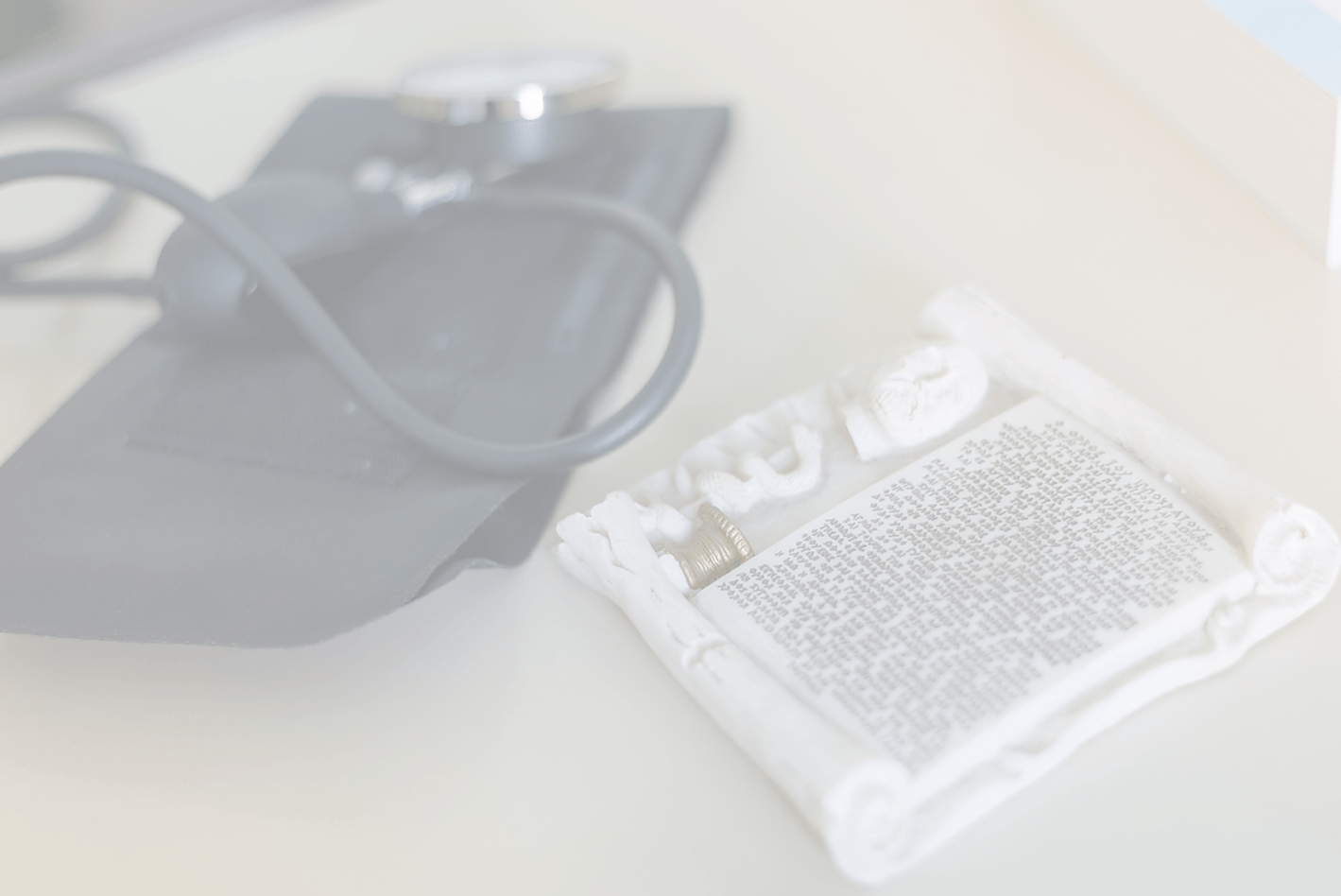 Miniature Hippocratic oath and blood pressure cuff sitting on a desk.