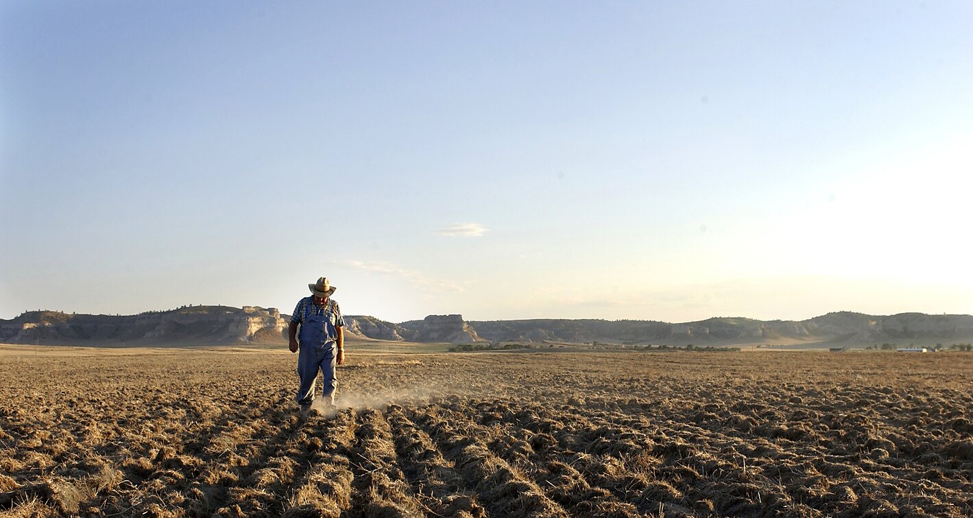 Farmer Bob Roberts walks in his dusty, cropless field, Scottsbluff, Nebraska, mid 2002.