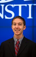 Smiling young man in a suit standing in front of the Cato Institute auditorium
